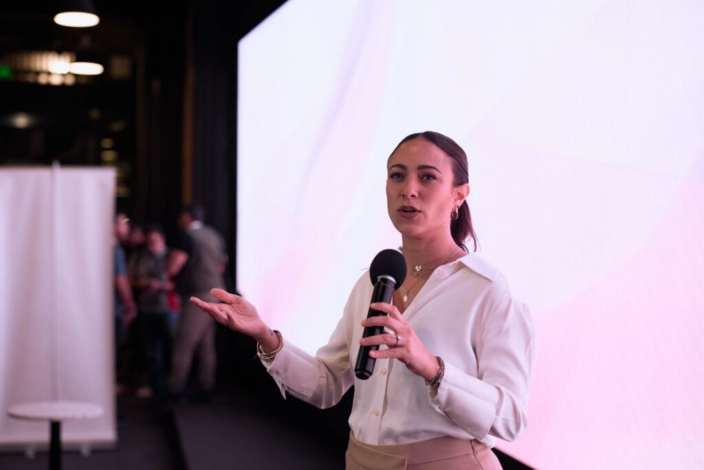 Woman giving a confident business presentation on stage with microphone at a modern conference