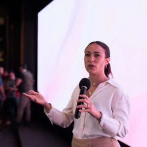 Woman giving a confident business presentation on stage with microphone at a modern conference